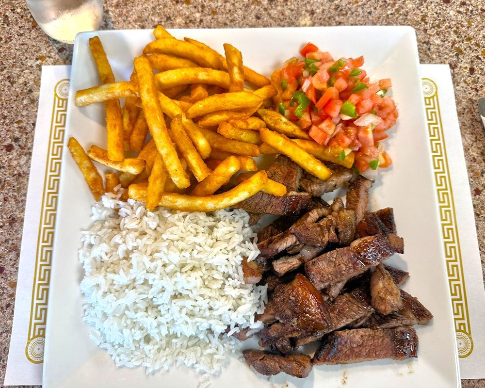 Plate of food with fries, rice, meat, and pico de gallo.