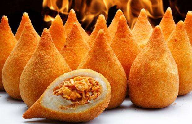 Close-up of Coxinhas, Brazilian fried chicken snacks with orange crispy coating and a chicken filling.