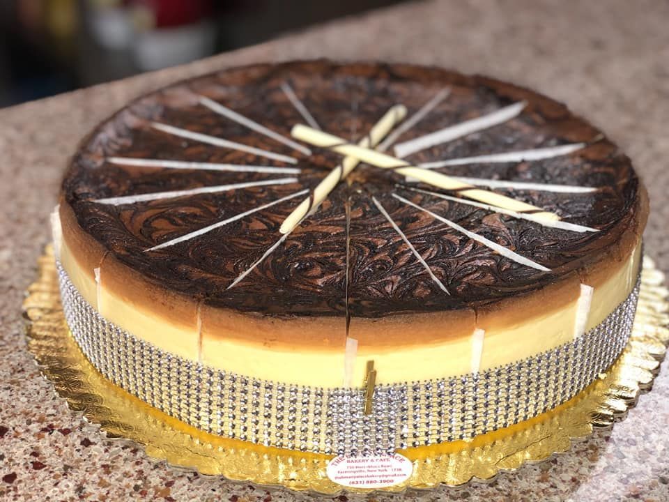Chocolate swirl cheesecake decorated with white chocolate, gold base, and jeweled ribbon.