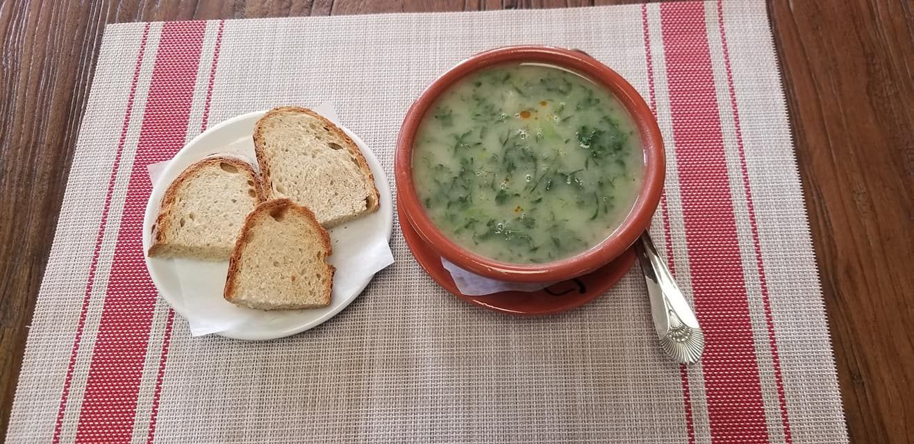 Soup with bread on a white plate, resting on a red and white placemat.