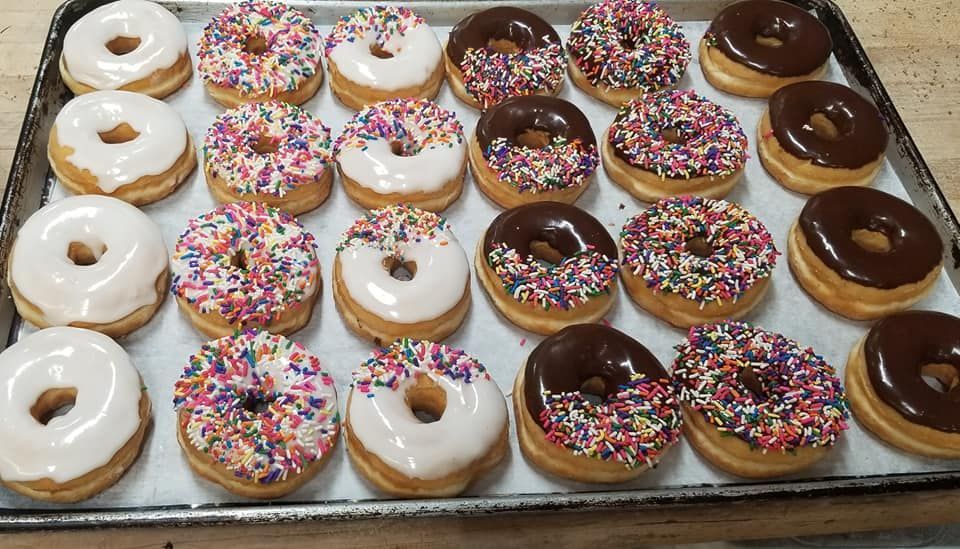 Tray of assorted donuts: glazed, sprinkles, and chocolate frosted.