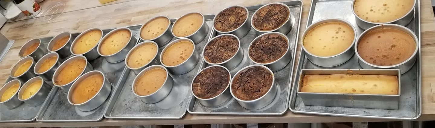Several baked cakes in metal pans on a tray, with variations in color and size.