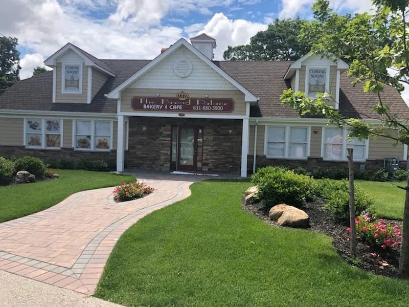 Building with a brick walkway leading to a brown door, surrounded by green grass and landscaping.