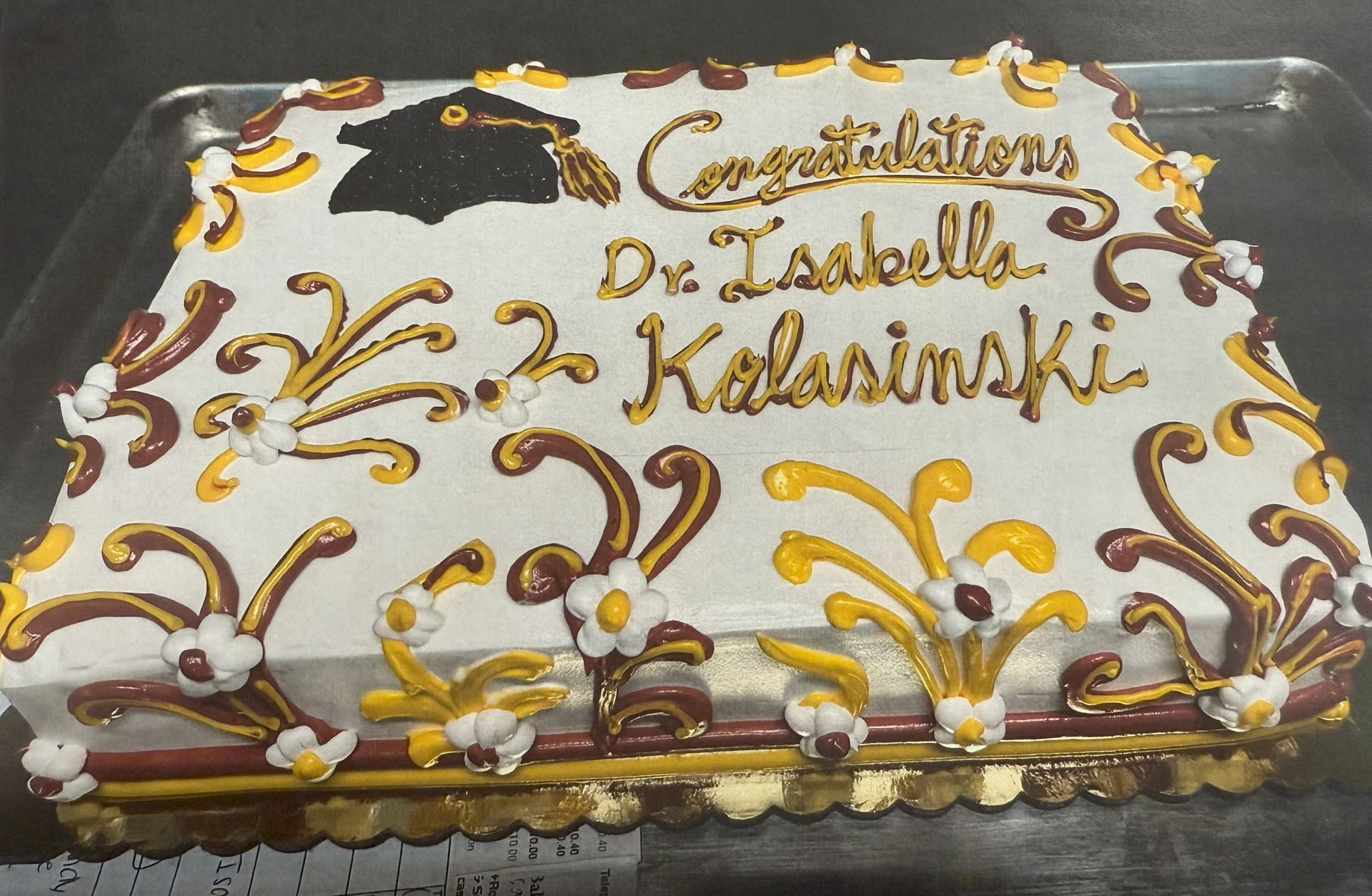 Graduation cake: white icing, gold/burgundy swirls, 