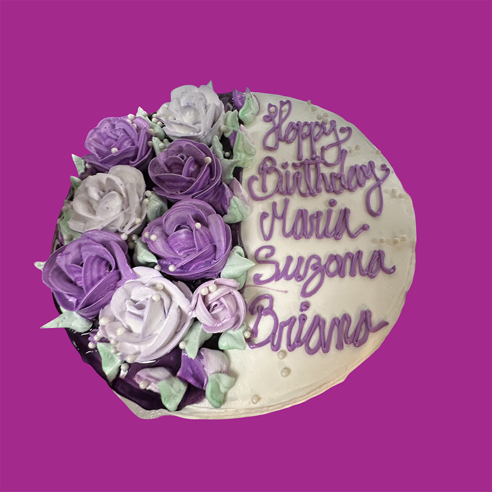 Cake decorated with purple and white flowers; text reads 
