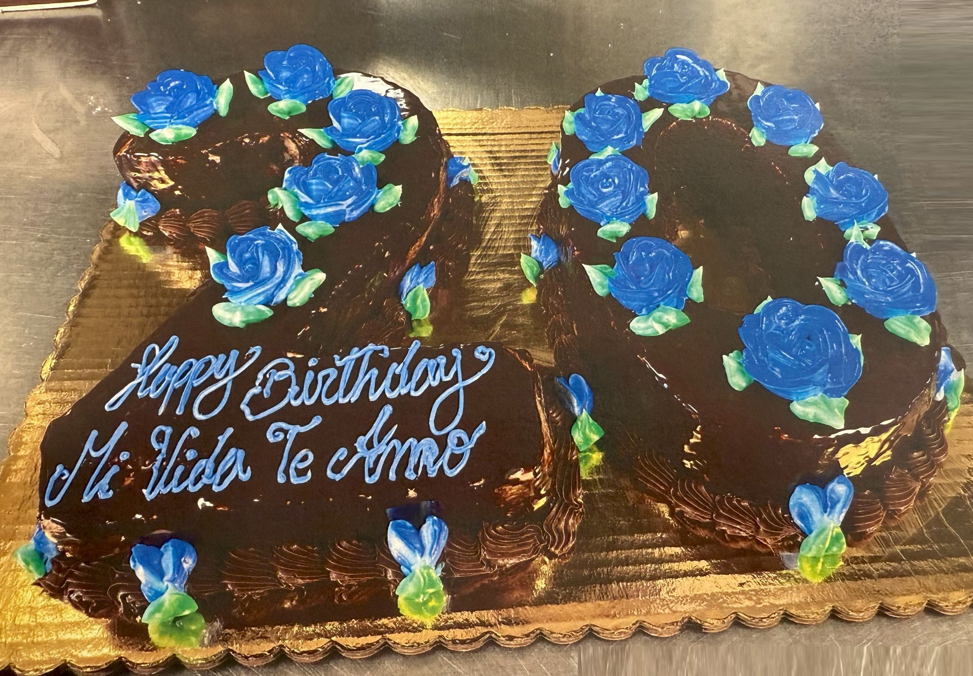 Chocolate cake shaped like the number 20, decorated with blue frosting roses and the message 