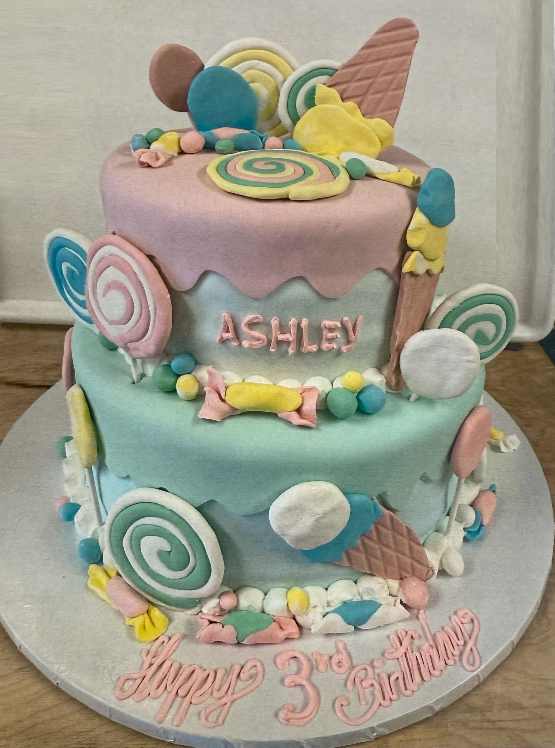 Two-tiered cake decorated with candy, lollipops, and frosting, for a birthday. Says 