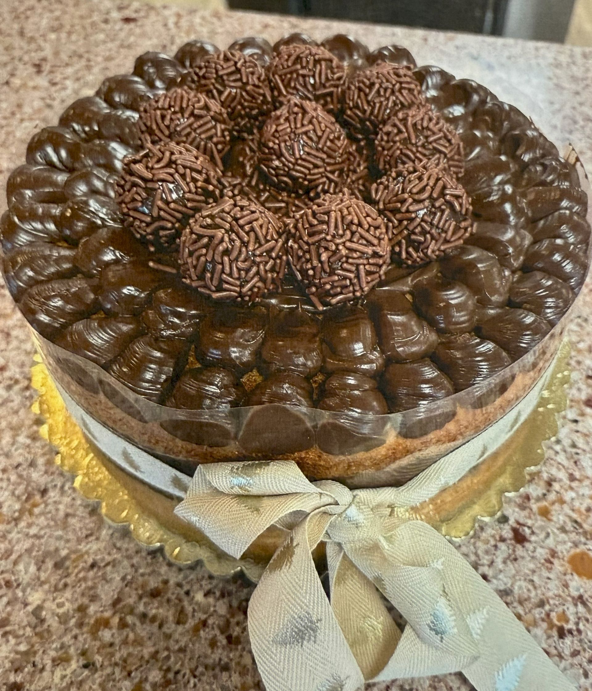 Cake with chocolate frosting and chocolate sprinkles, tied with a ribbon.