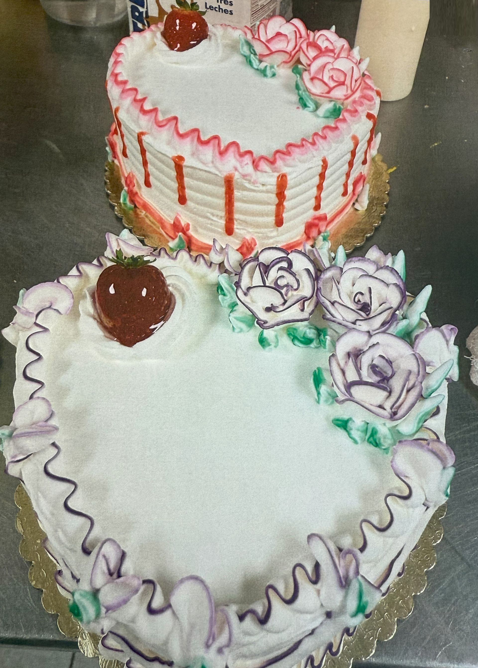 Two heart-shaped cakes decorated with frosting roses and strawberries.