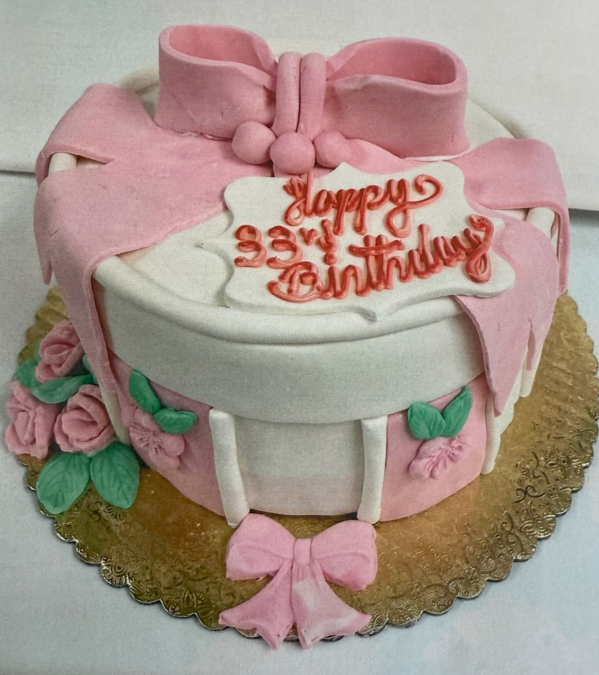 Pink and white birthday cake with a bow design and 