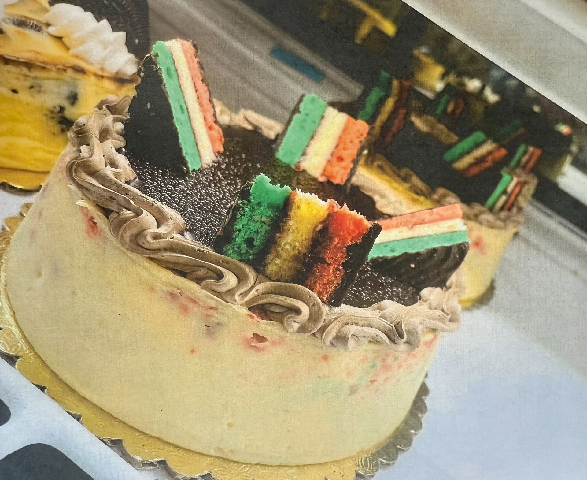 Cake with colorful layered cookies and chocolate frosting on a gold cake board.