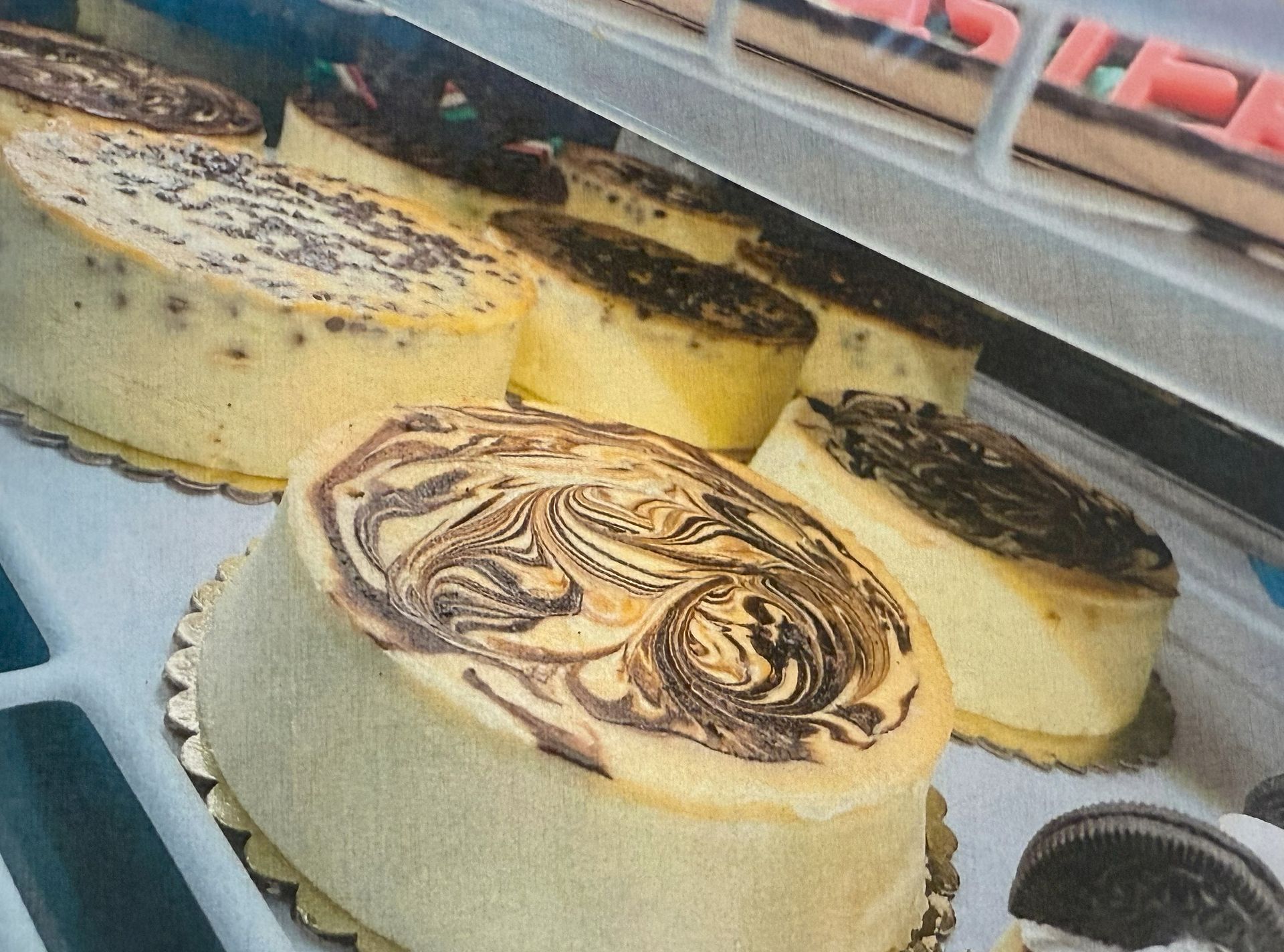 Cheesecakes in a display case with various toppings, including a marbled design.