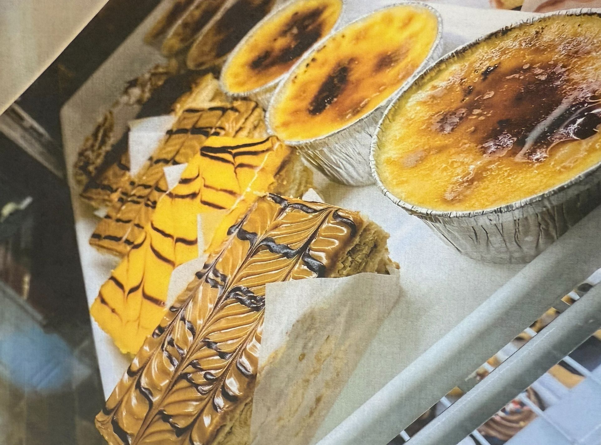 Display case with desserts, including crème brûlée and layered pastries.