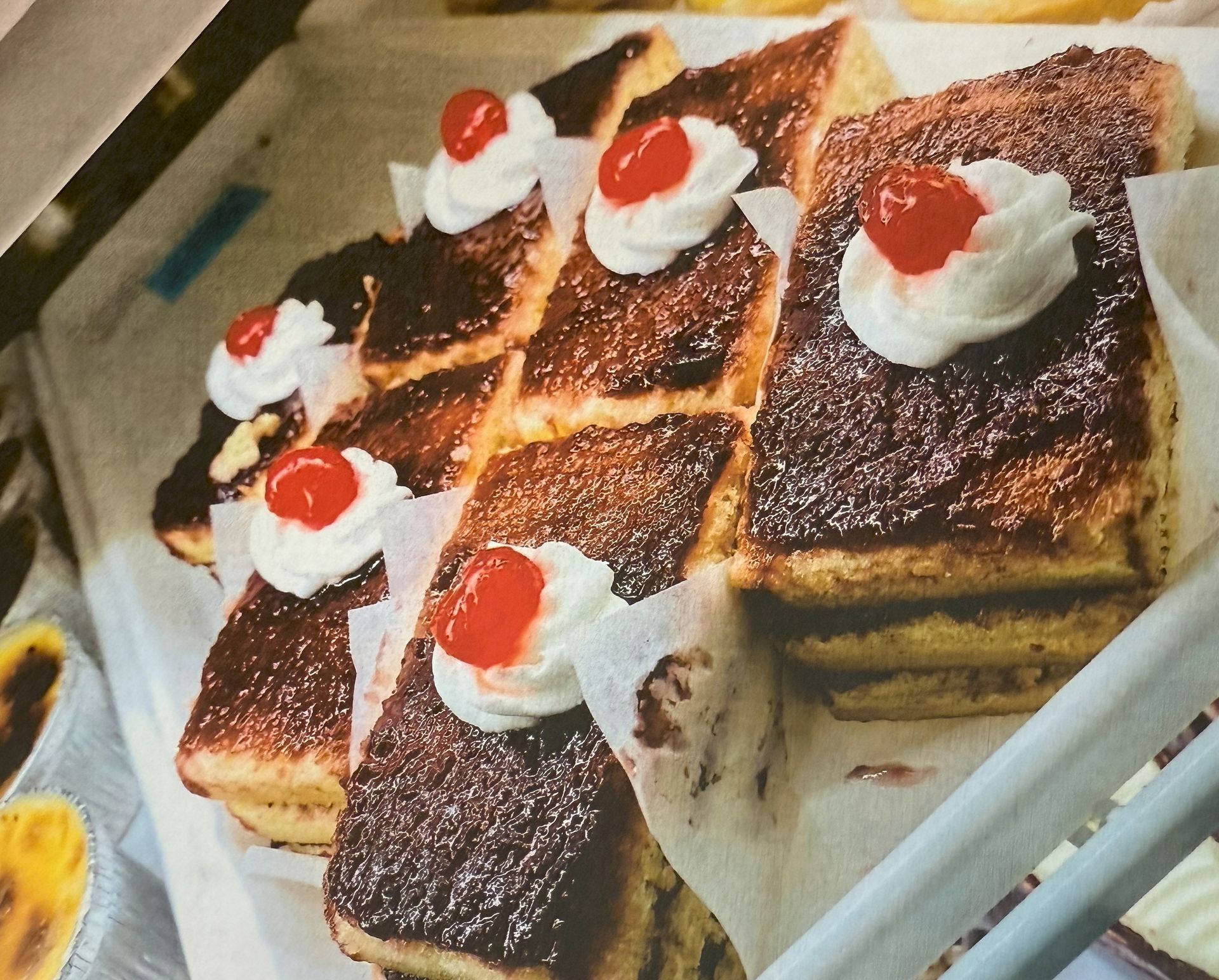 Rectangular pastries topped with whipped cream and a cherry.