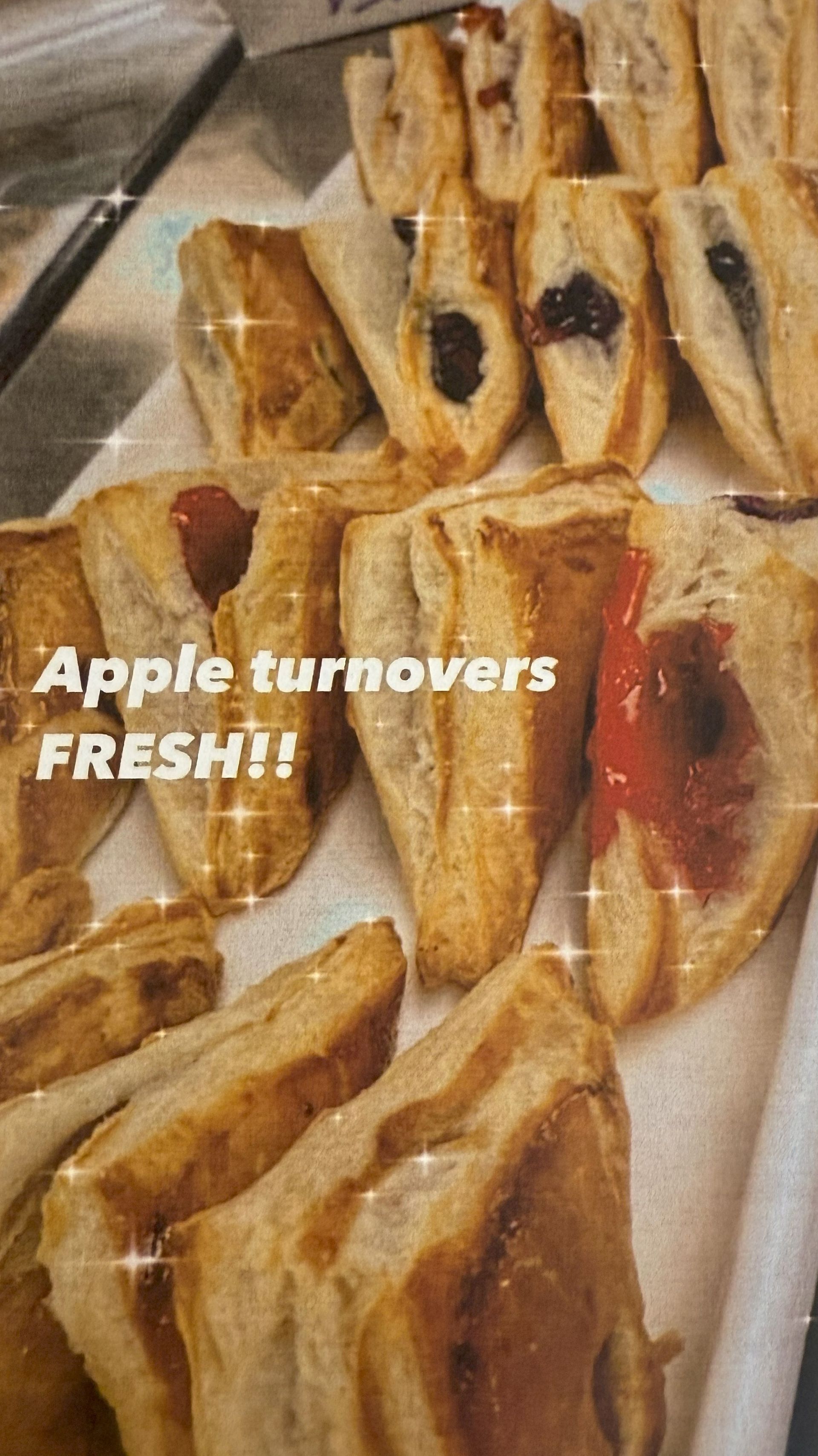 Apple turnovers, some with fillings, arranged on a tray. Freshly baked and golden brown.