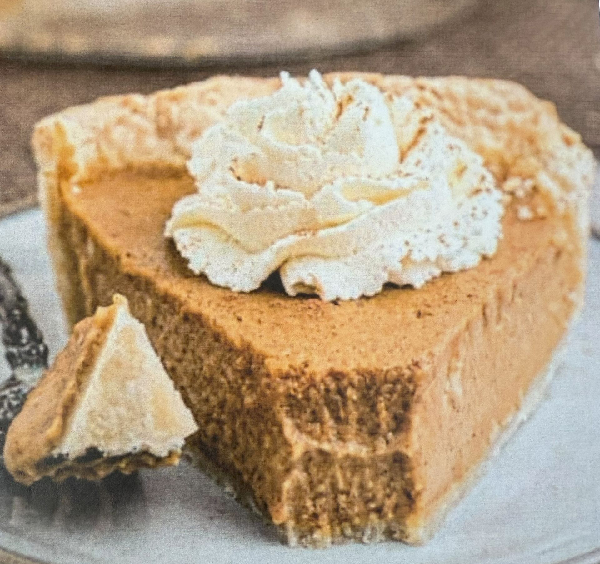 Slice of pumpkin pie with whipped cream on a plate.