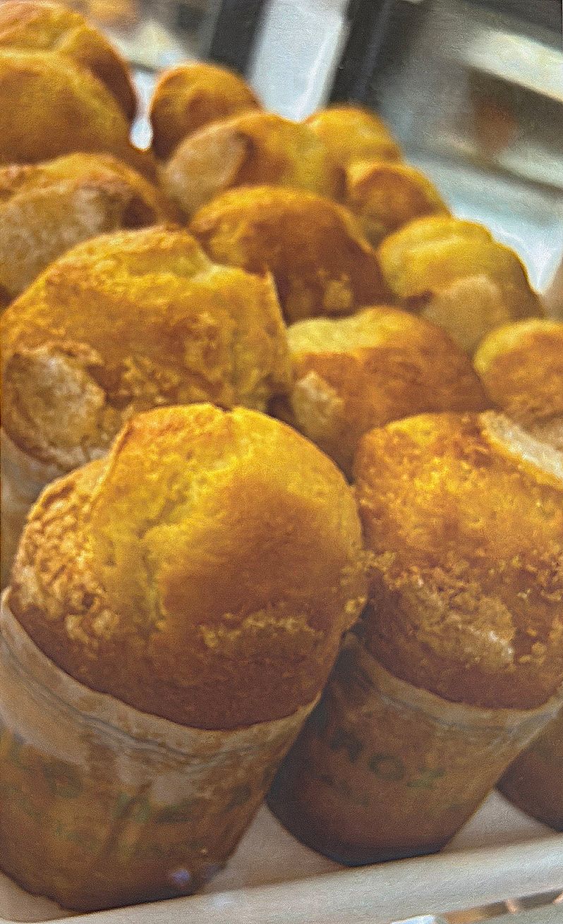 Golden muffins in paper cups, displayed in a bakery setting.