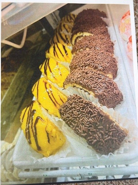 Display case of pastries: yellow glazed and chocolate sprinkle-covered, on a white tray.
