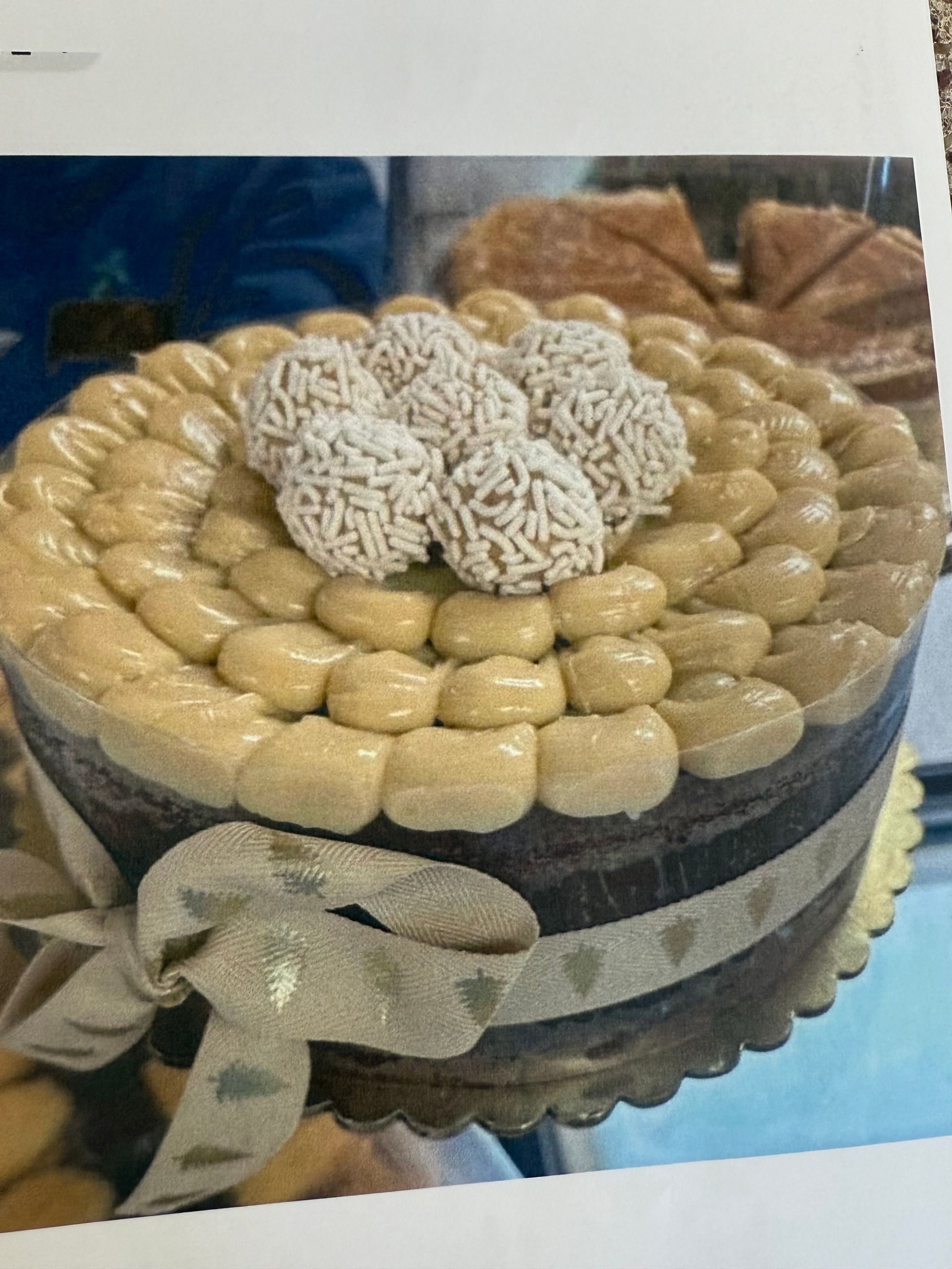 Chocolate cake with cream frosting and decorative truffles, tied with a patterned ribbon.