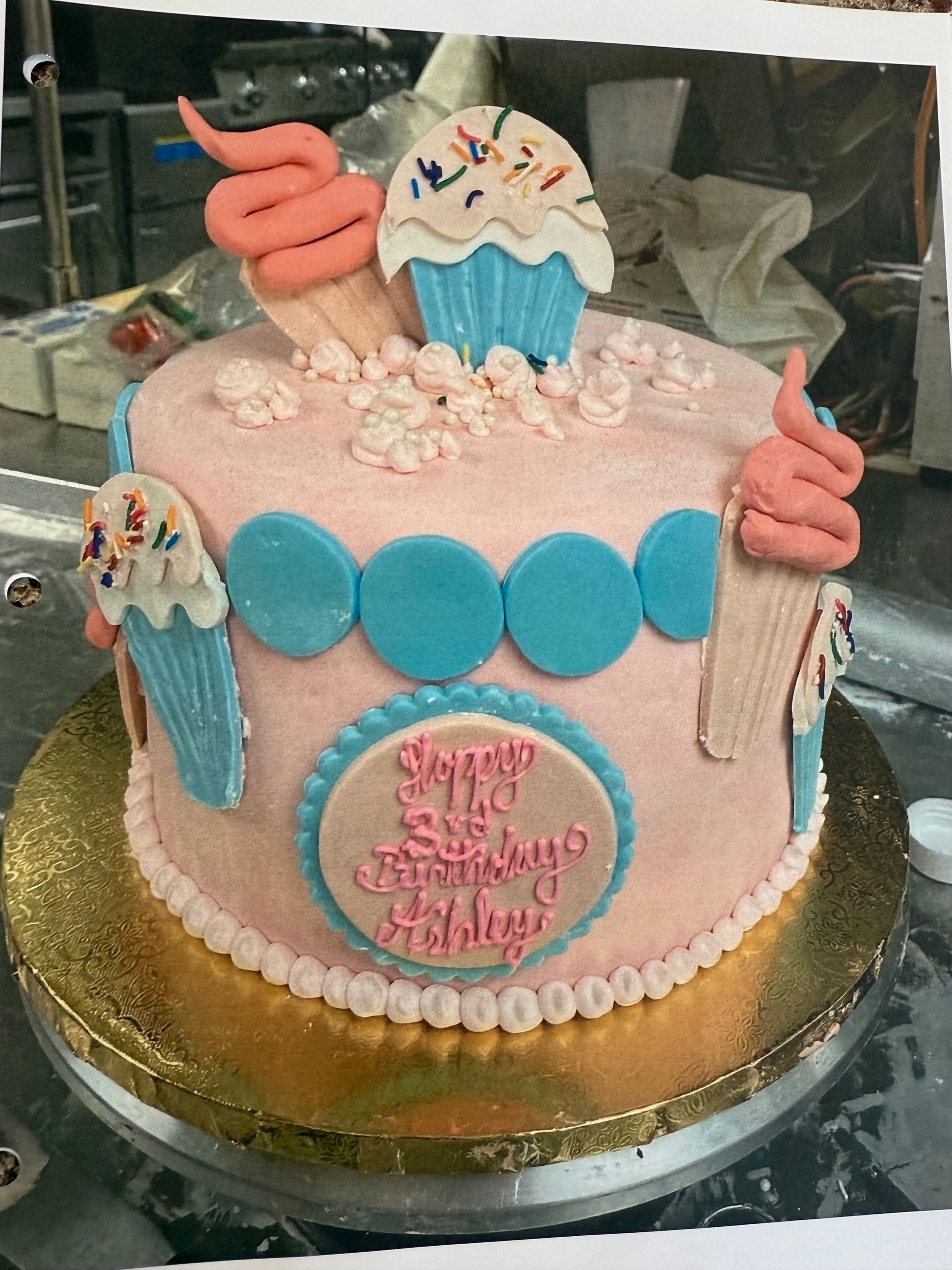 Pink cake with blue accents, decorated with ice cream cones and a message.