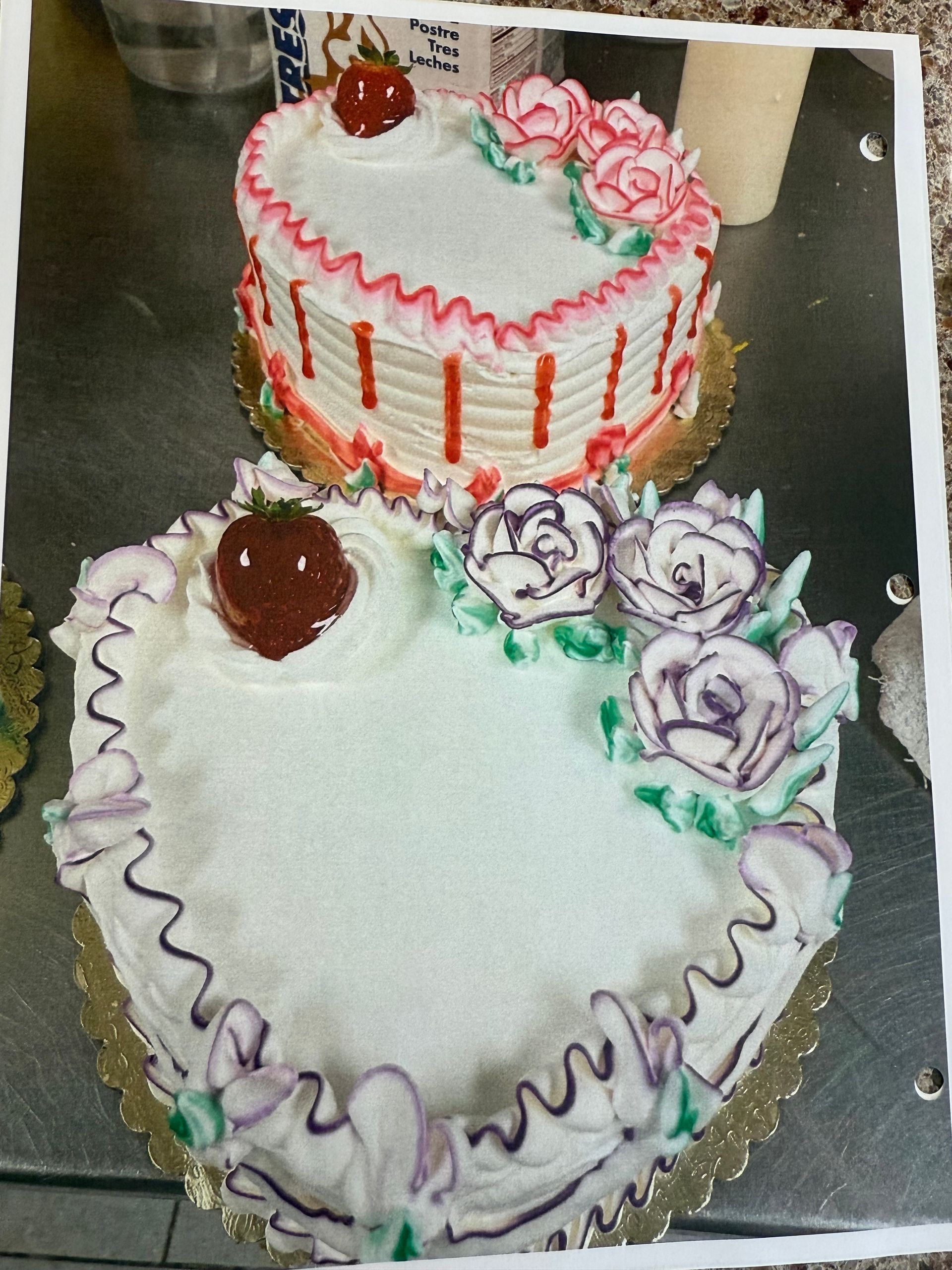 Two heart-shaped cakes with white frosting, decorated with roses and strawberries.
