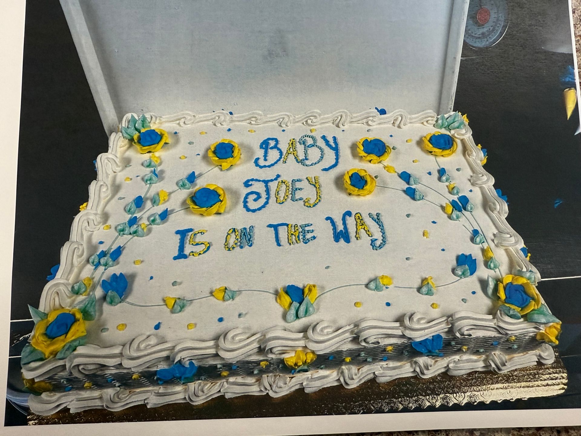 White rectangular baby shower cake with blue and yellow floral decorations and 