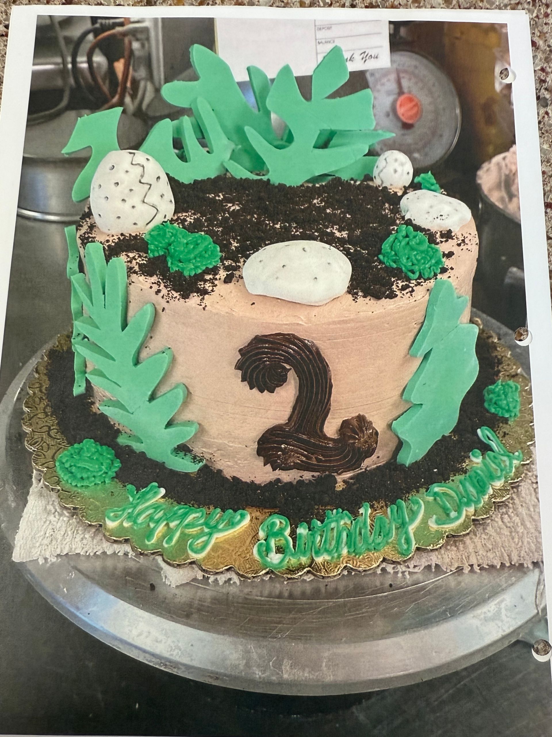 Dinosaur-themed birthday cake with green ferns, eggs, and 