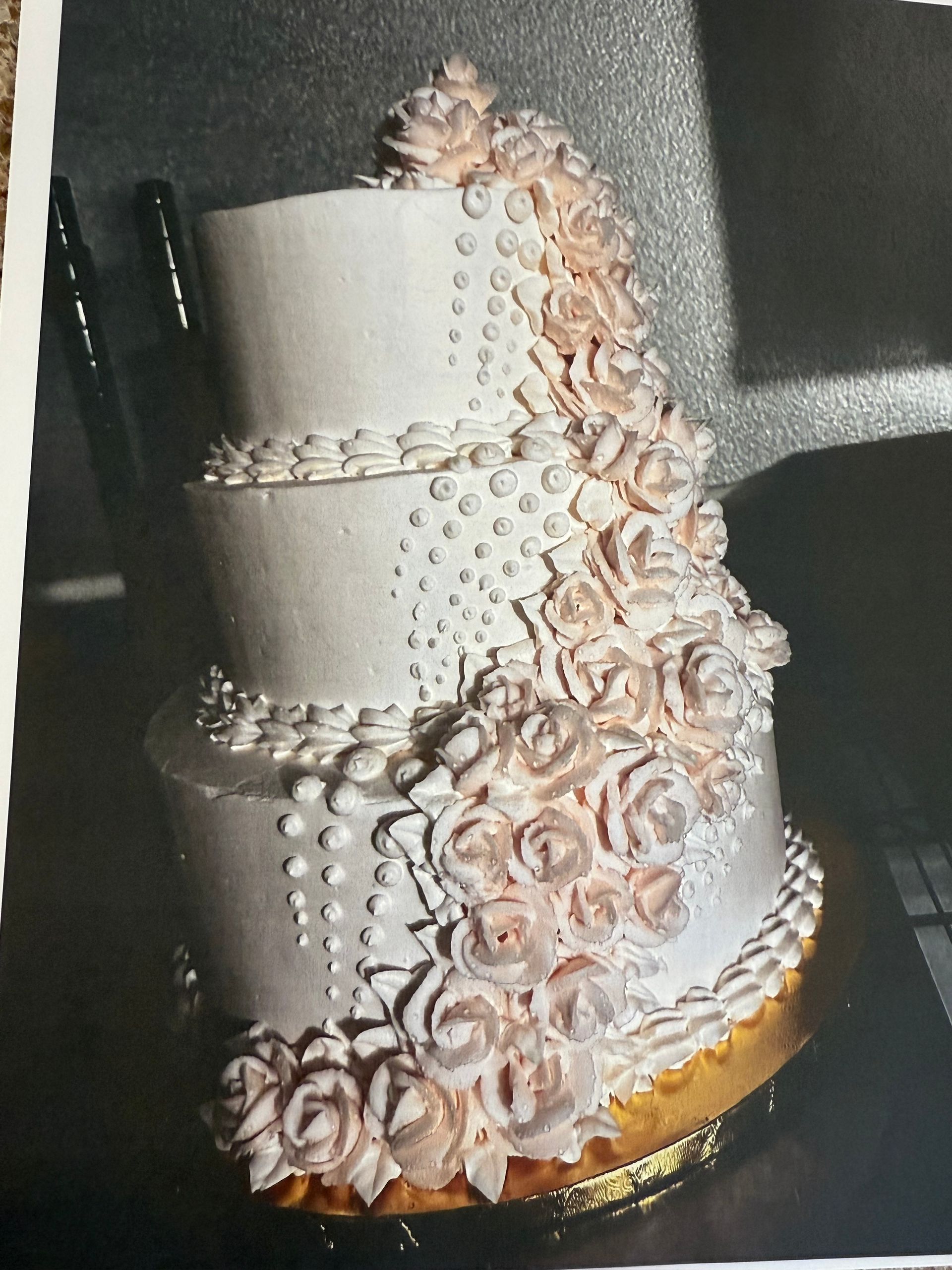 Three-tiered cake decorated with pink roses and white icing.