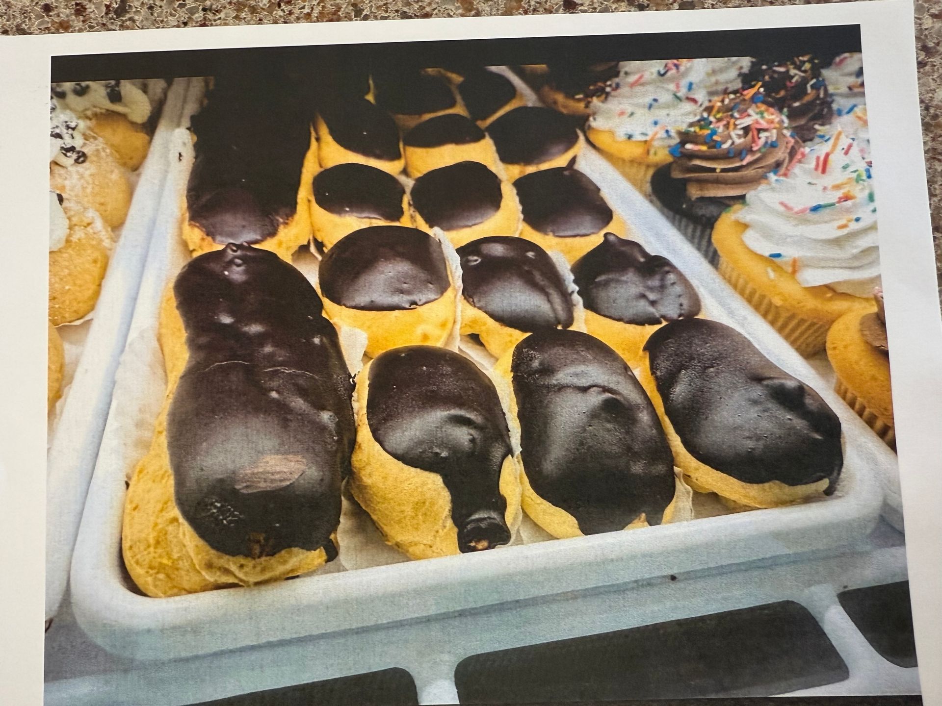 Tray of chocolate eclairs and assorted donuts.