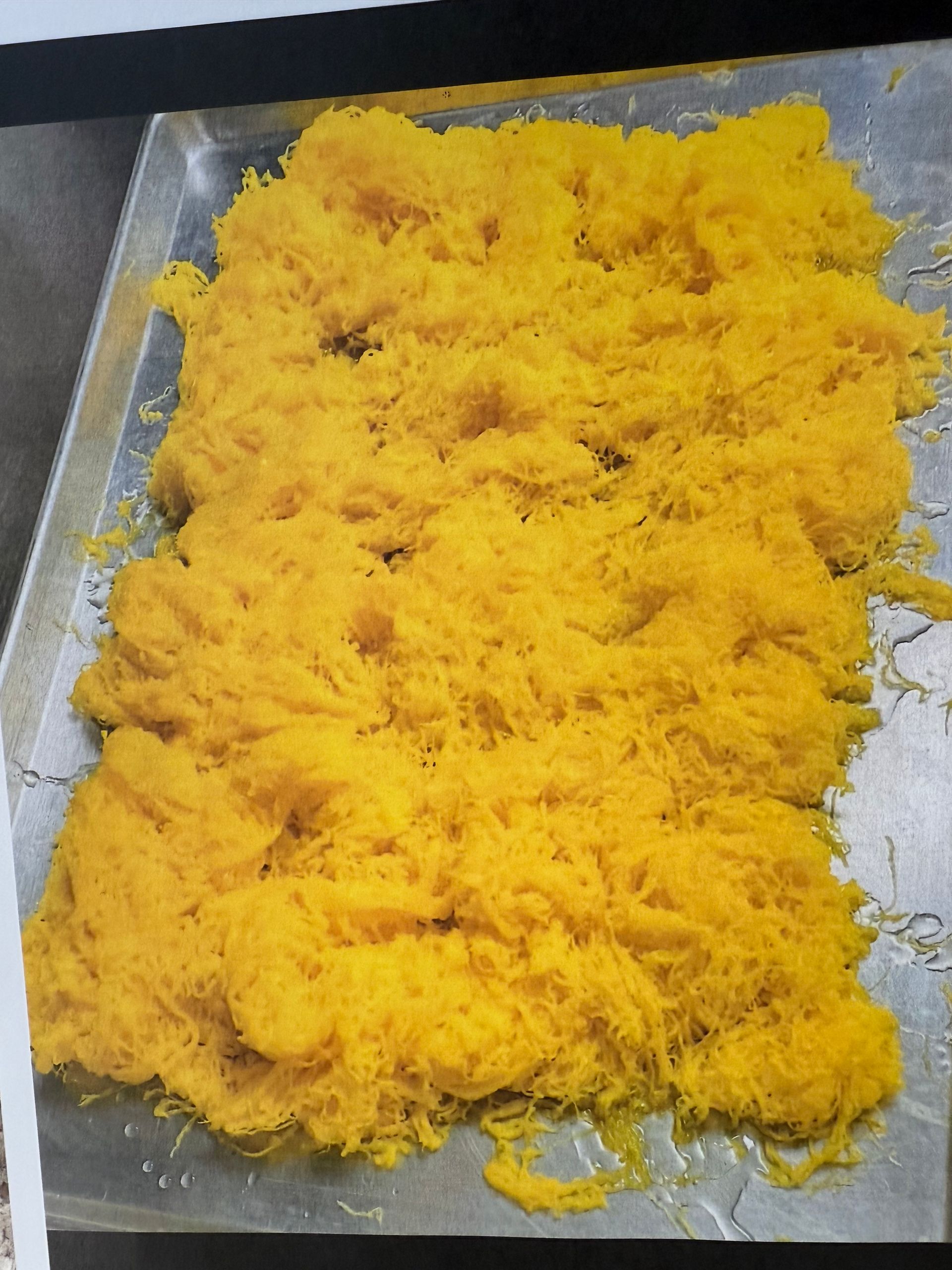 Golden-yellow shredded dessert on a metal tray.
