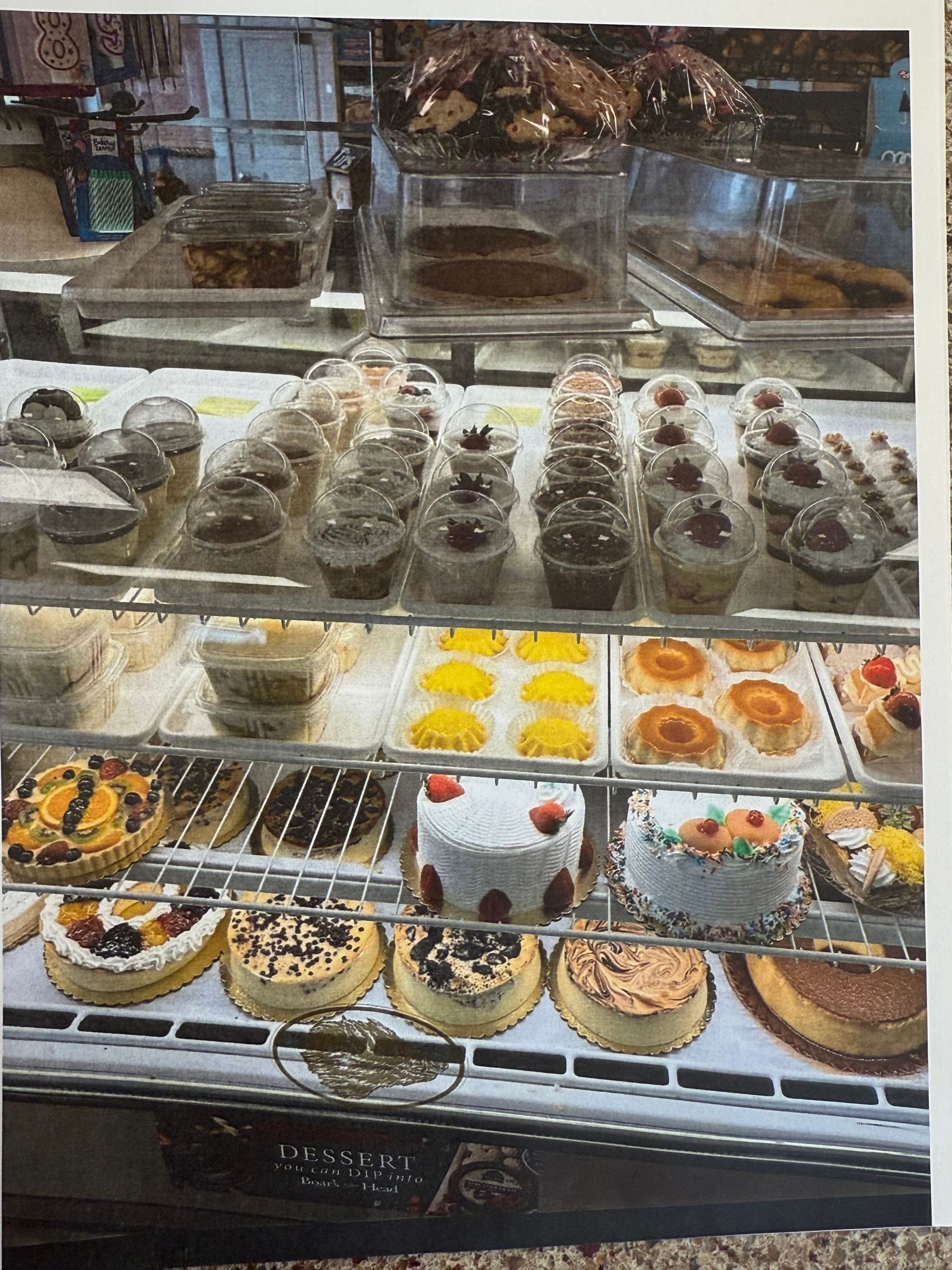 Bakery display case filled with various cakes, pastries, and cupcakes.
