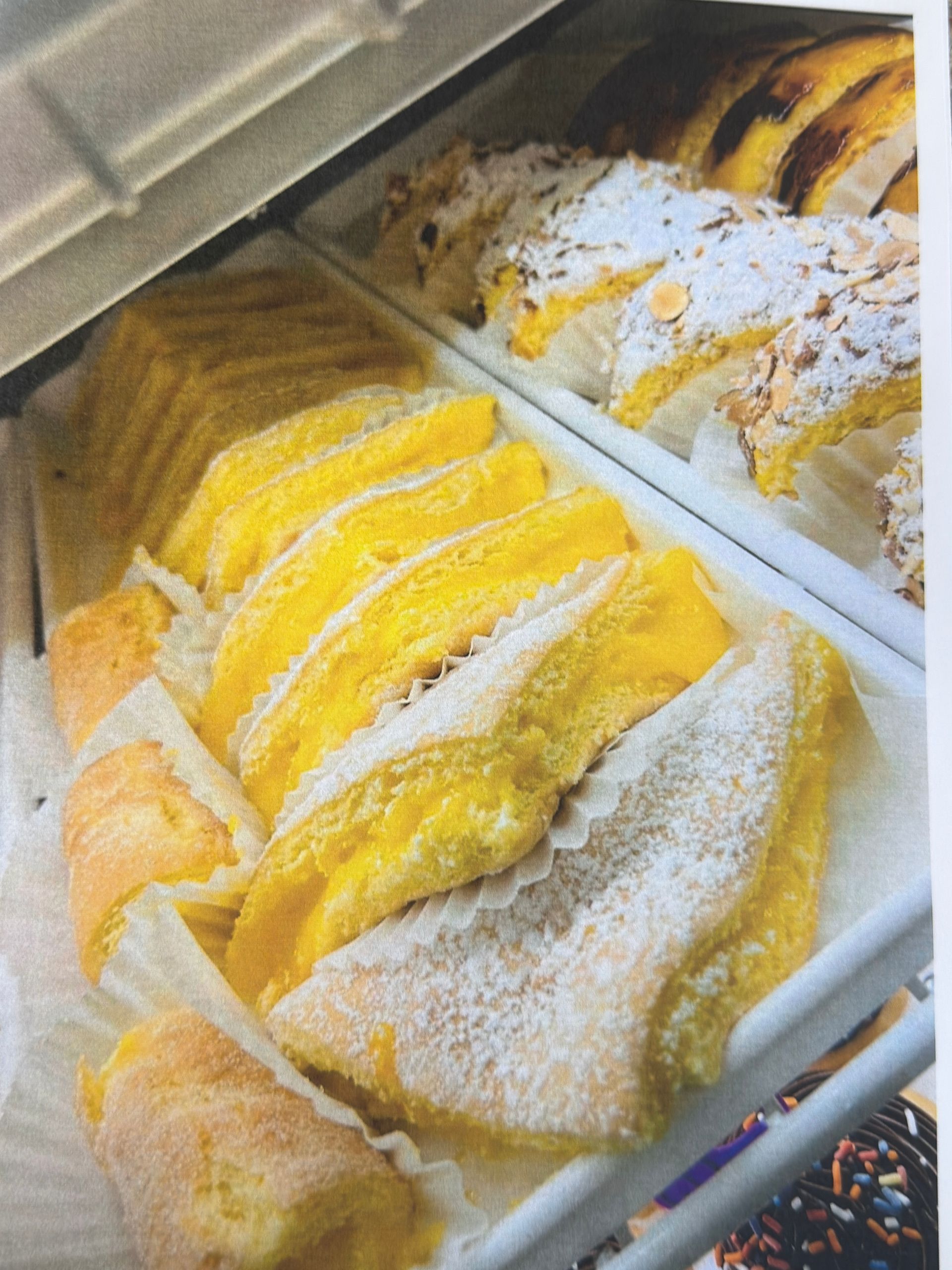Pastries in a display case; yellow and white frosted, sugared pastries.