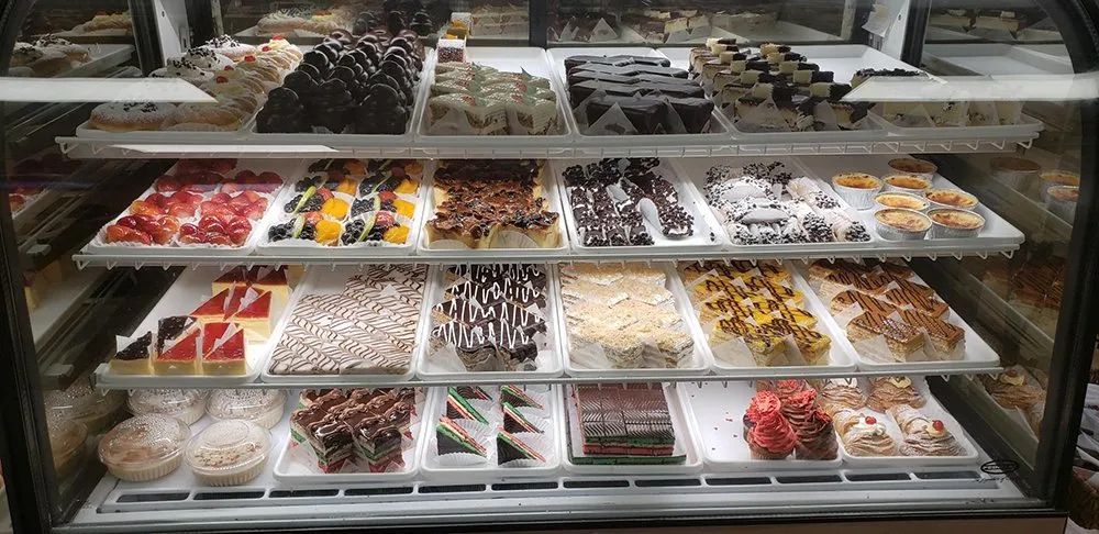 A display case filled with various cakes and pastries at a bakery.