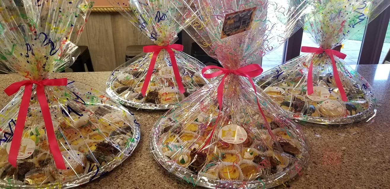 Four dessert platters wrapped in cellophane with red bows.