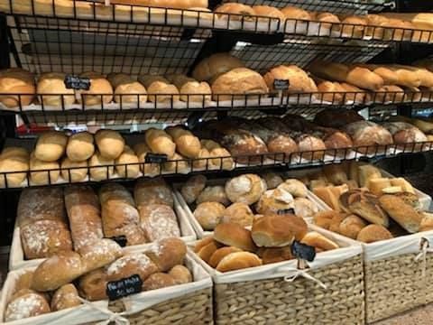 Shelves of various breads in a bakery. Baskets hold rolls, baguettes, and loaves.