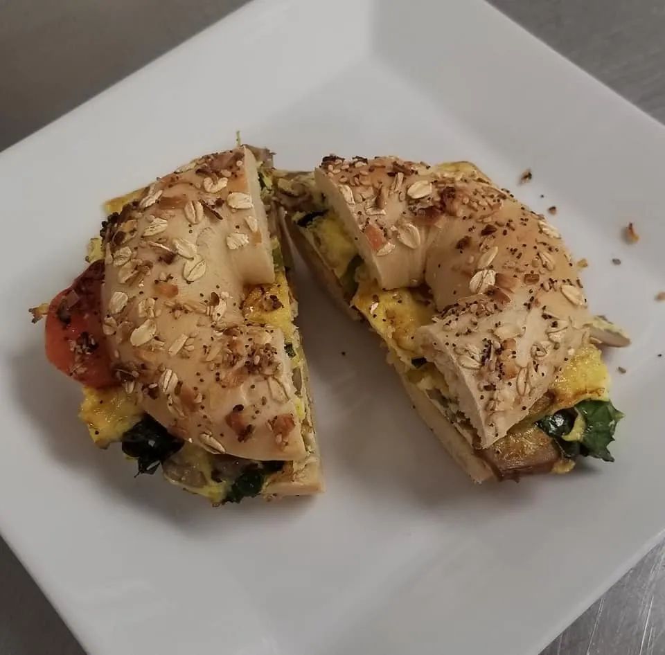 Everything bagel sandwich cut in half on a white plate.