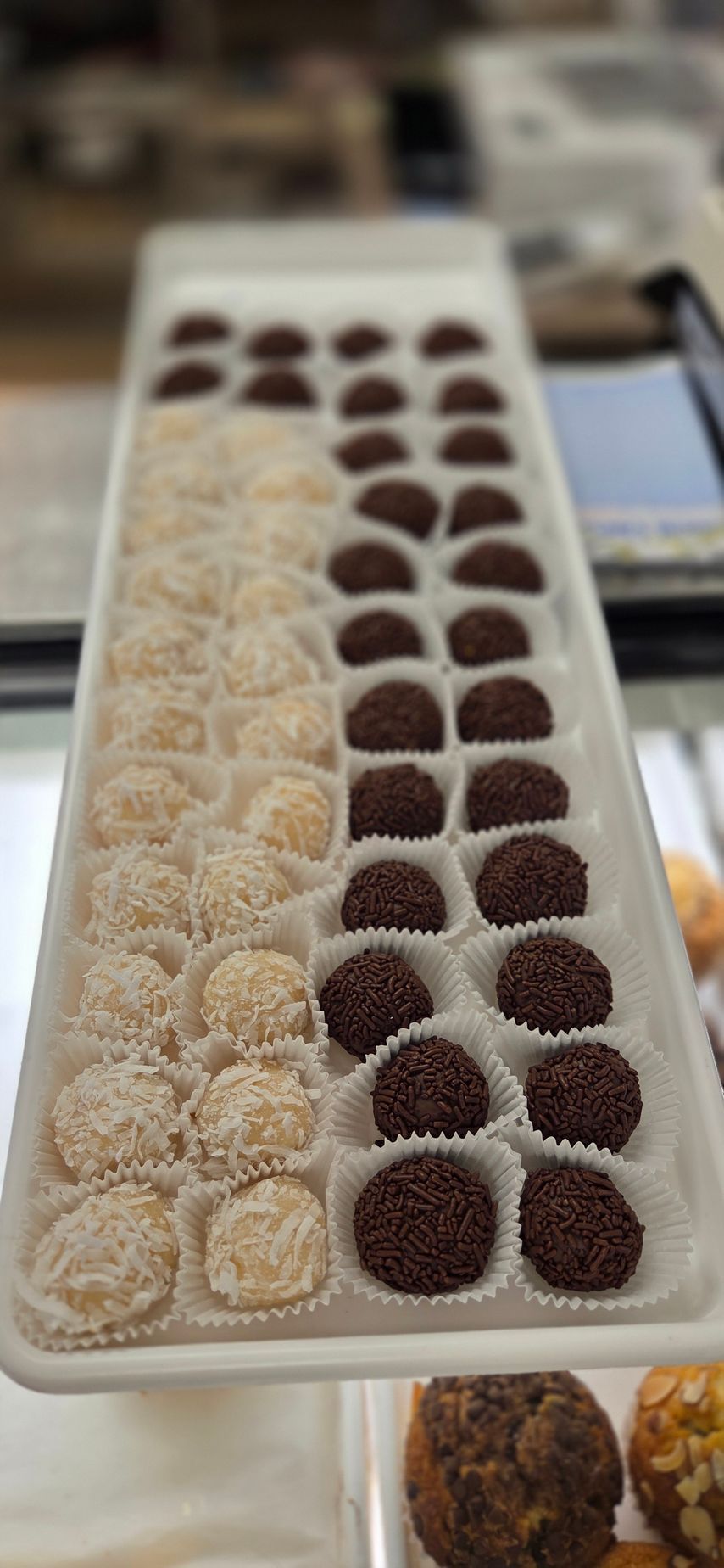 Tray of white and dark chocolate truffles in a display case.