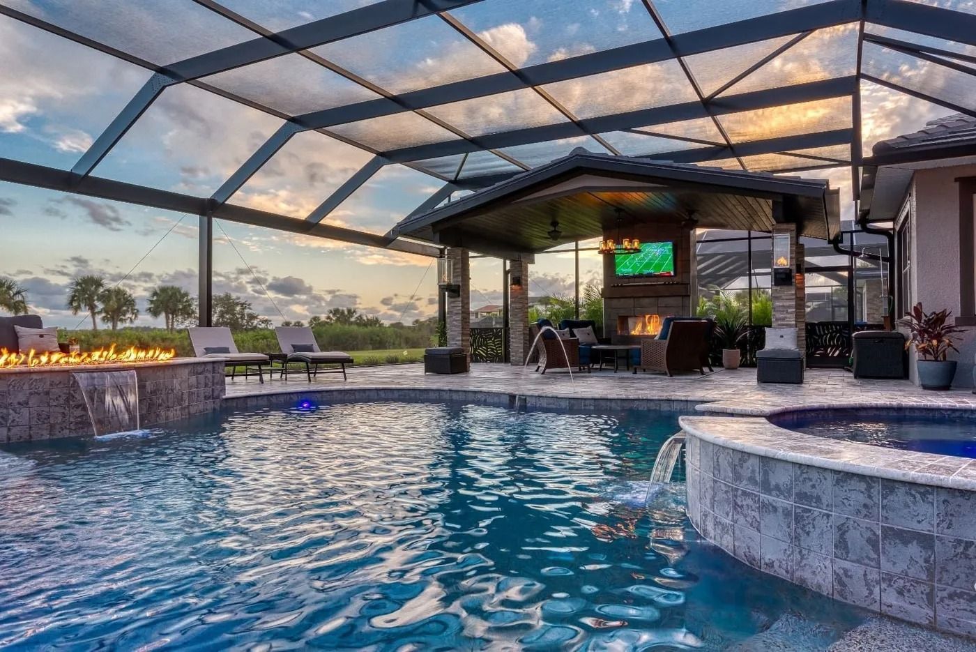 Pool area with screen enclosure, water features, outdoor fireplace, and seating.
