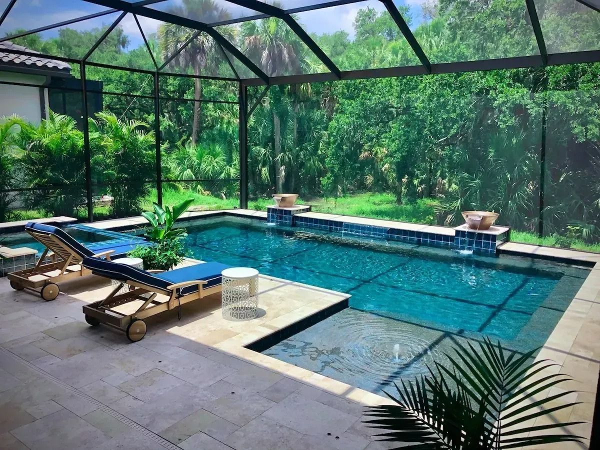 Pool area with screened enclosure, pool, lounge chairs, and lush greenery.