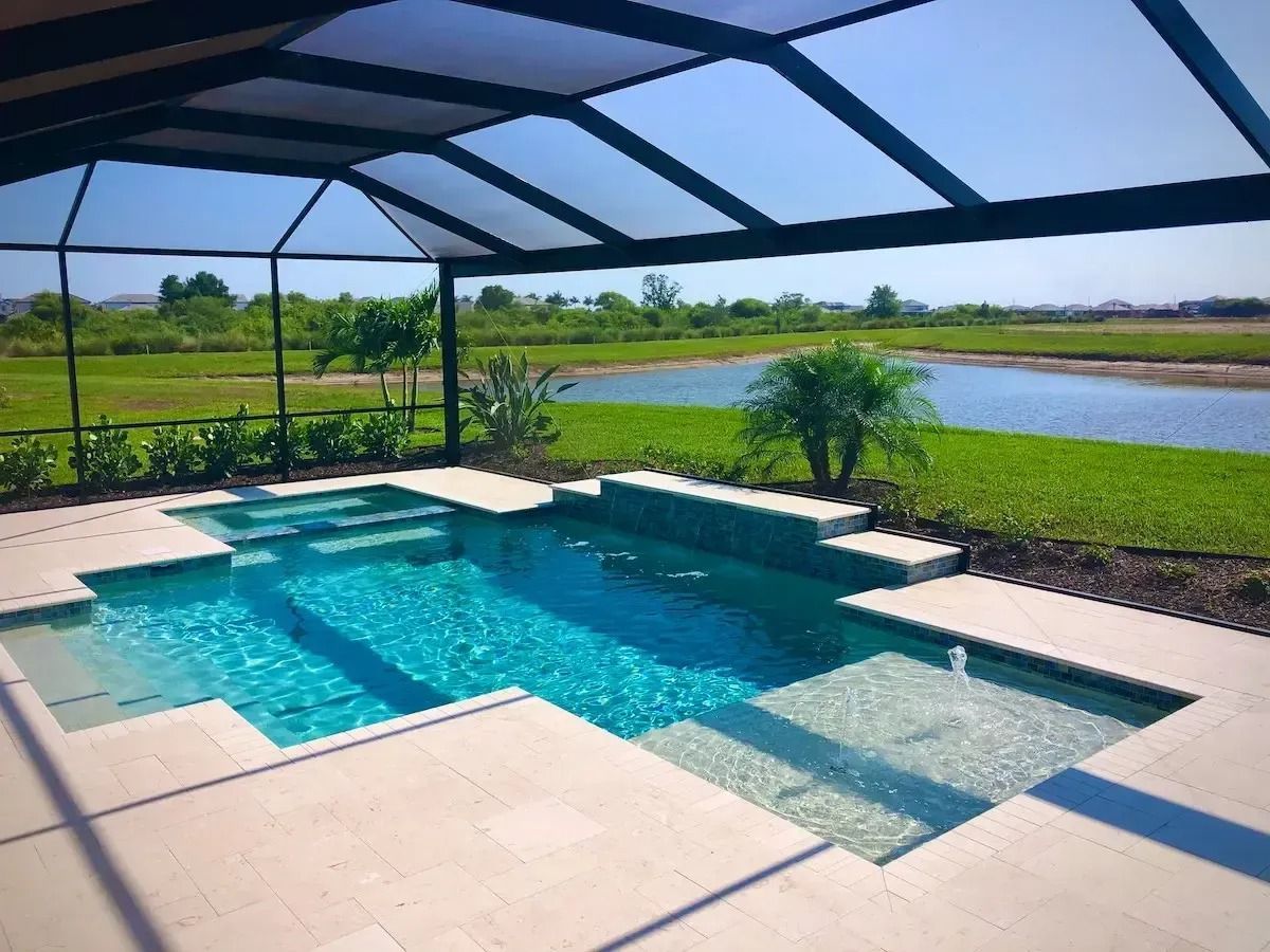 Pool under screened enclosure overlooking a lake and grassy landscape.
