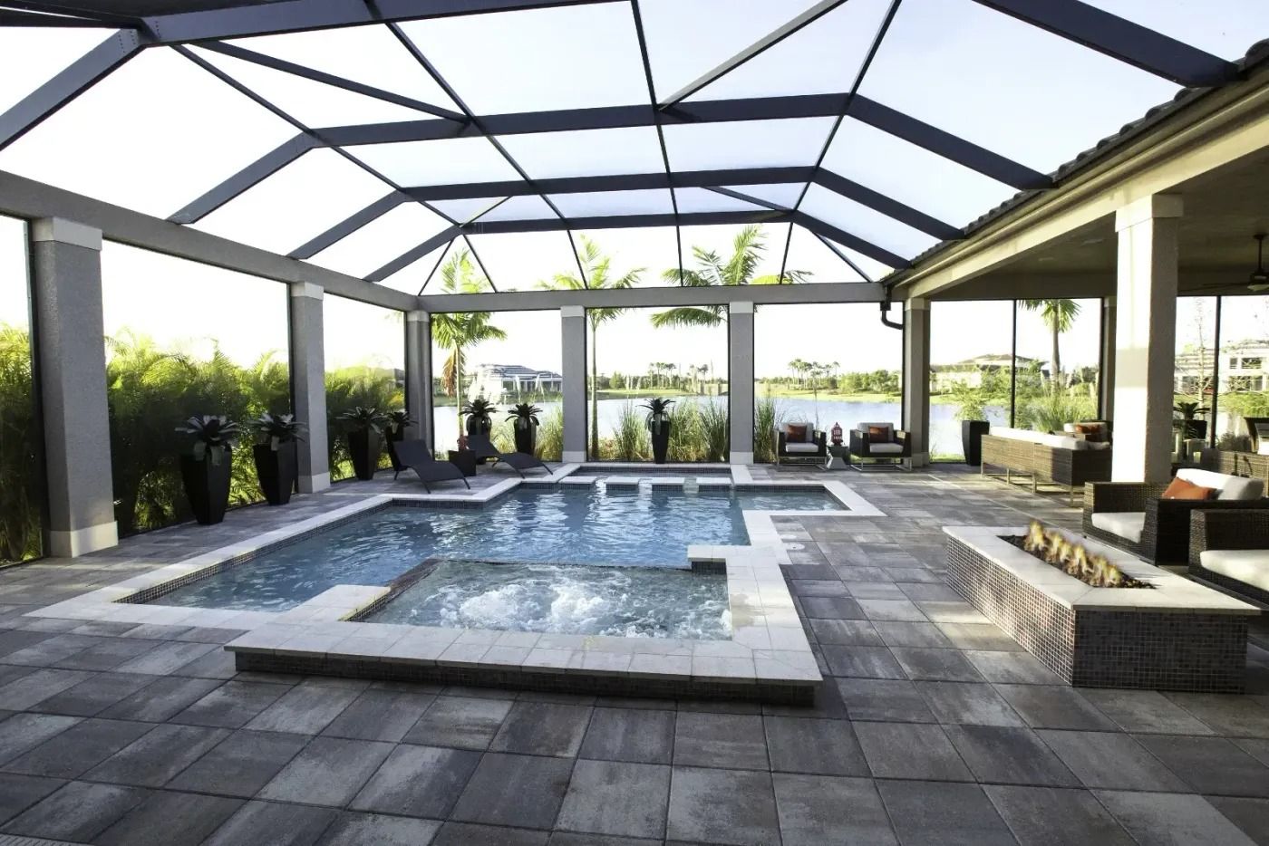 Backyard pool with screen enclosure, patio, fire pit, lake view, and lounge chairs.