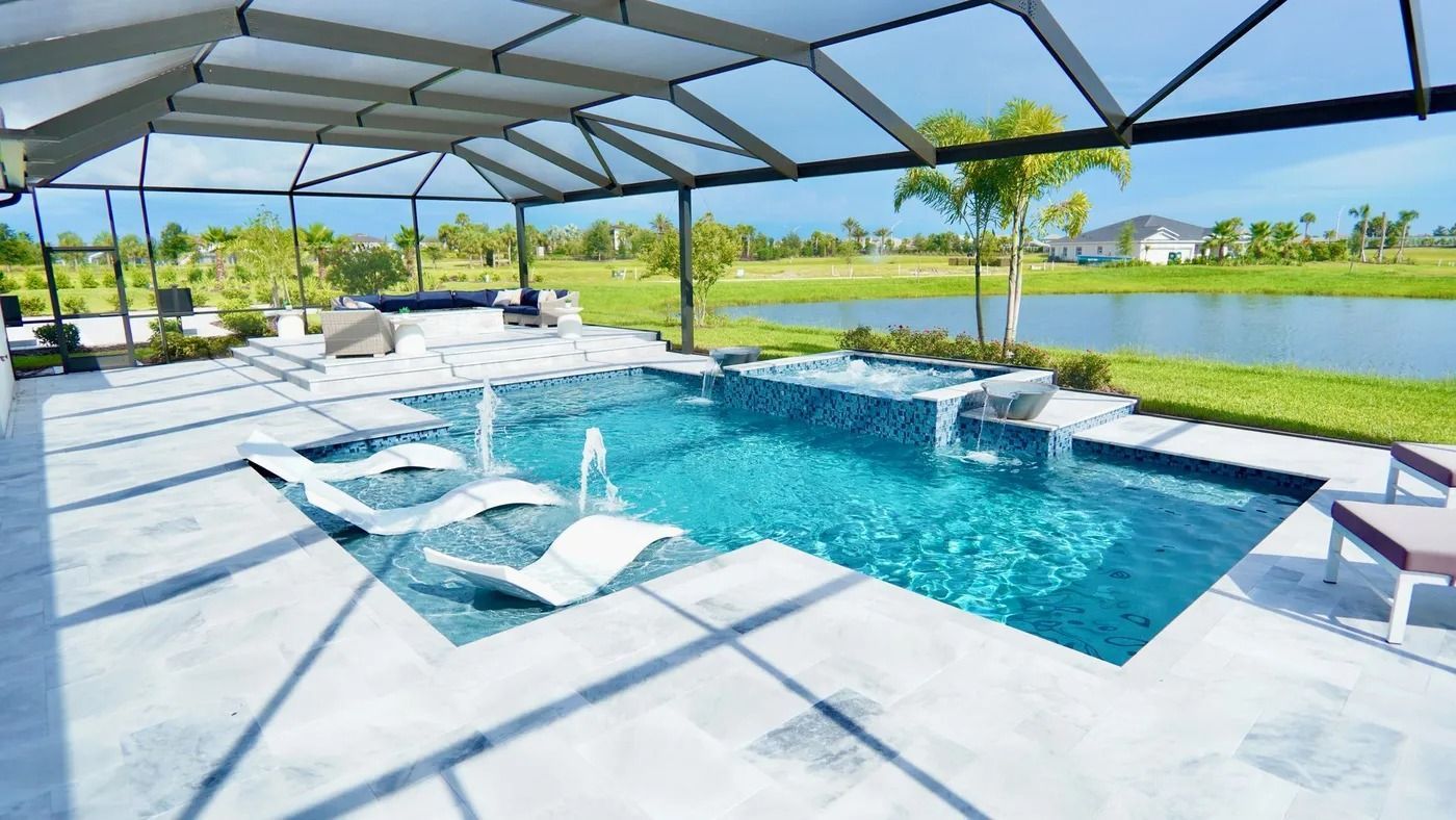 Pool with white chaise lounges and fountains, under a screened enclosure, overlooking a lake.