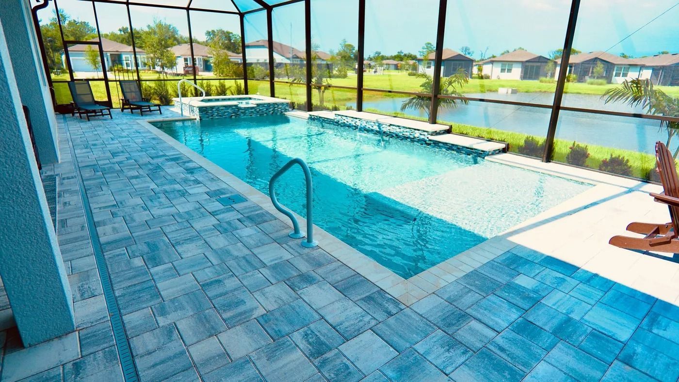 Poolside view with pool, spa, pavers, and water backdrop. Enclosed by screen.