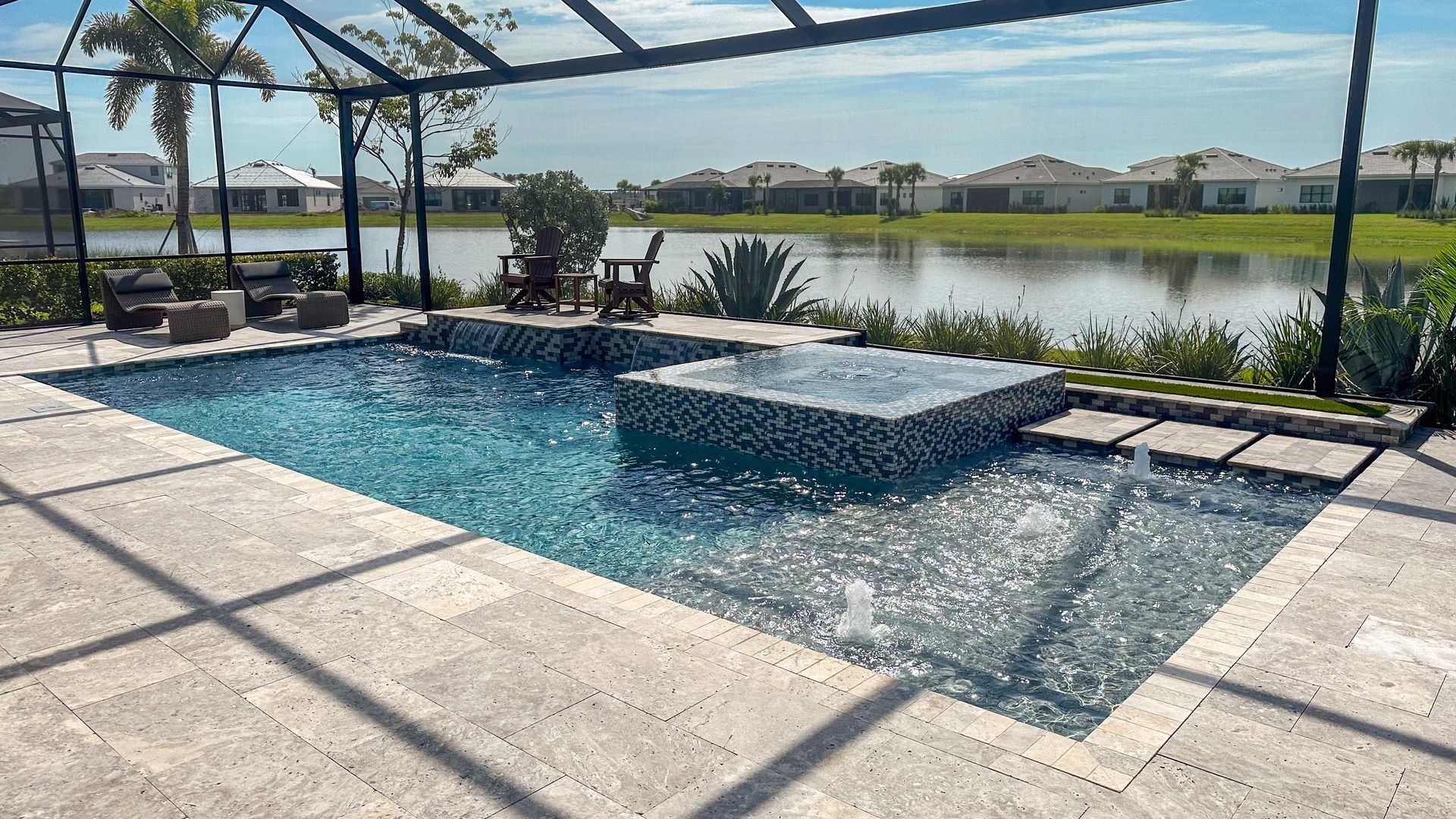 Backyard pool with a raised spa, screened enclosure, and lake view in bright sunlight