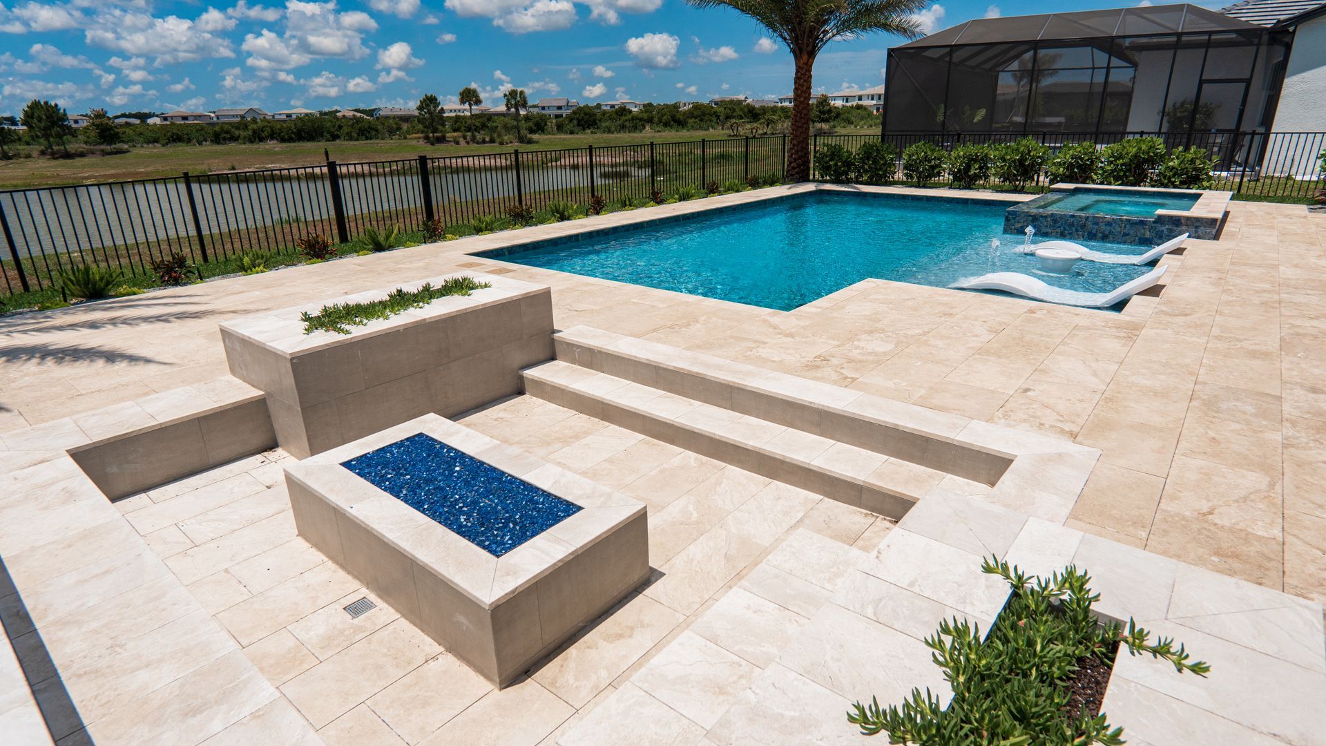 Backyard pool with stone patio, built-in benches, and a small blue-tiled water feature