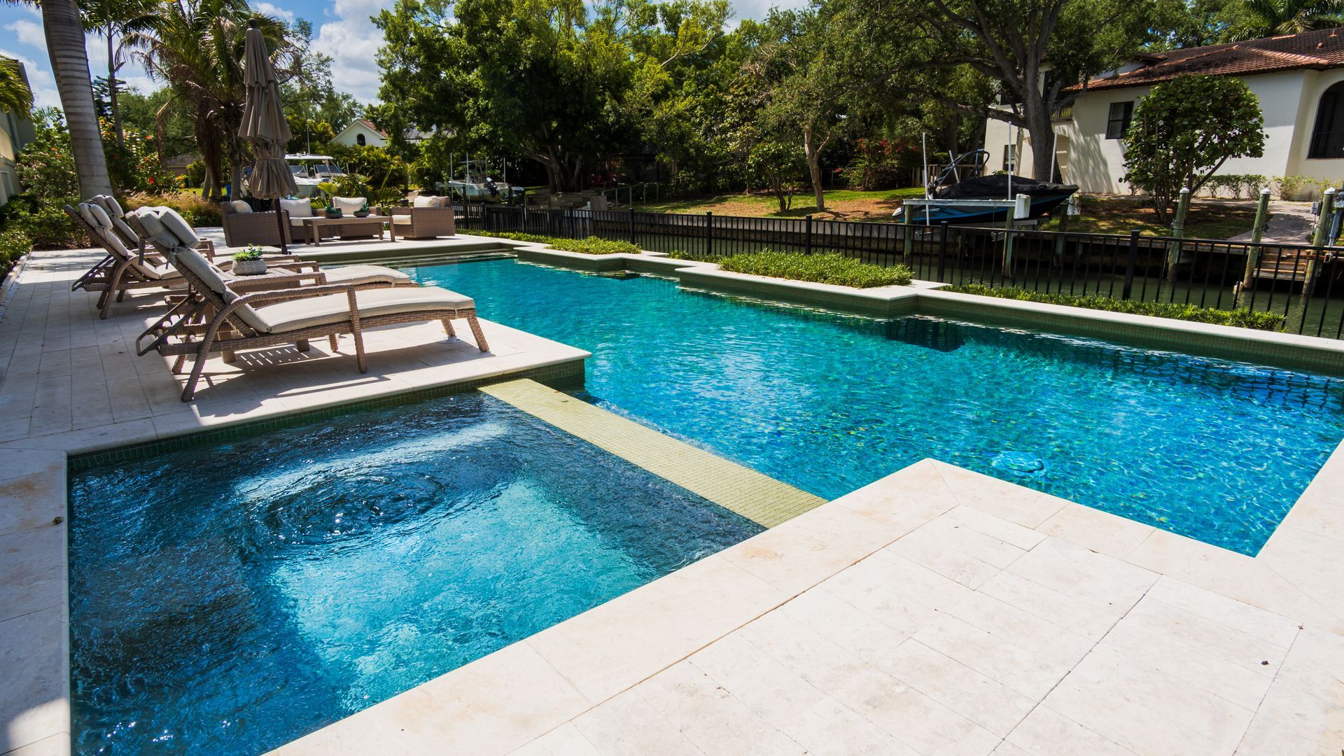 Modern resort pool with blue water, lounge chairs, and trees in the background