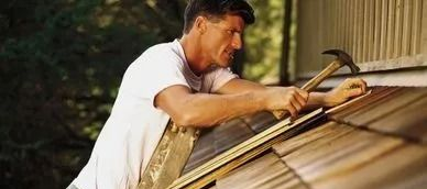 A person on a roof hammers a shingle.