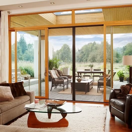 Living room with large sliding glass doors, view of patio with furniture, natural landscape.
