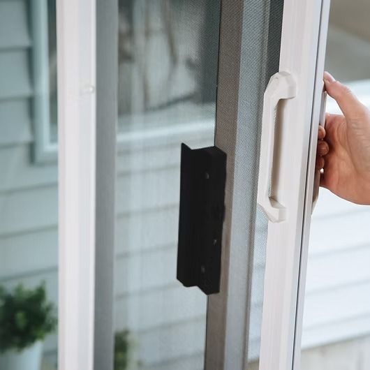 White sliding glass door with hand opening it. Black handle on door frame.
