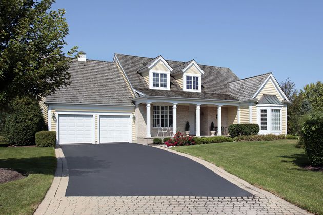Yellow house with white trim, two-car garage, and driveway on a sunny day.